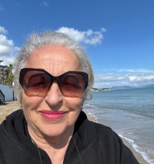 Şöhret Küçükay — deniz kenarında, gülümseyen ak saçlı yazar